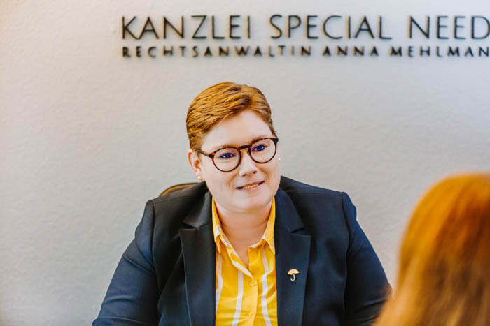 Anwältin Anna Mehlmann im Gespräch mit einer von hinten aufgenommenen Person in einem Besprechungsraum der Kanzlei Special Needs.